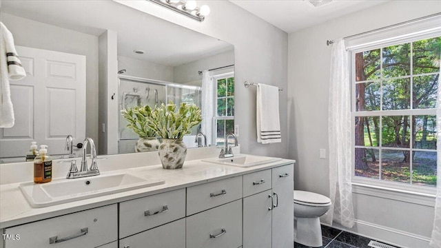 full bath featuring double vanity, a stall shower, a sink, and baseboards