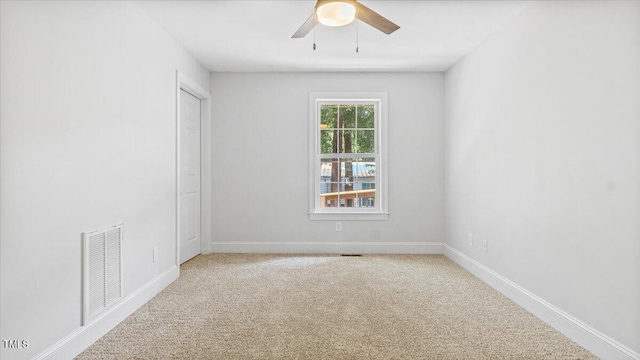 carpeted spare room featuring ceiling fan, visible vents, and baseboards