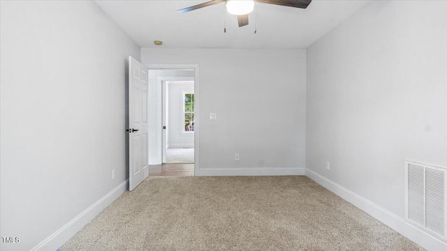 carpeted spare room with baseboards, visible vents, and ceiling fan