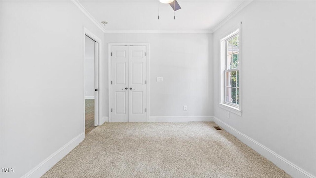 carpeted empty room featuring baseboards, visible vents, and ornamental molding