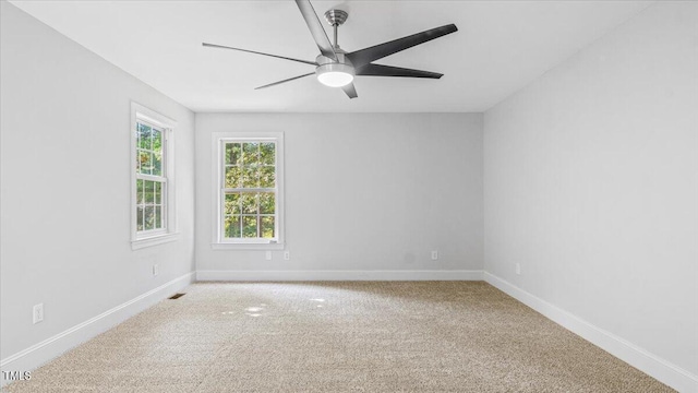 empty room with carpet flooring, ceiling fan, visible vents, and baseboards