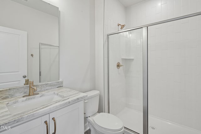 bathroom with a shower stall, toilet, and vanity