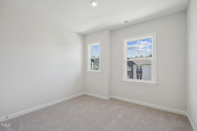 empty room with light carpet, visible vents, and baseboards