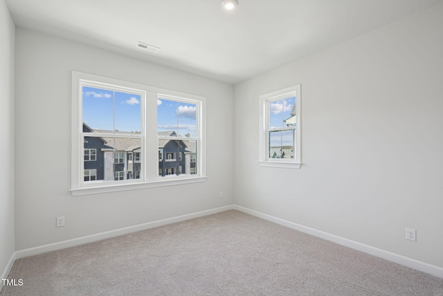 carpeted spare room with visible vents, baseboards, and a wealth of natural light