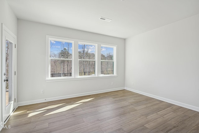 unfurnished room with baseboards, visible vents, and wood finished floors