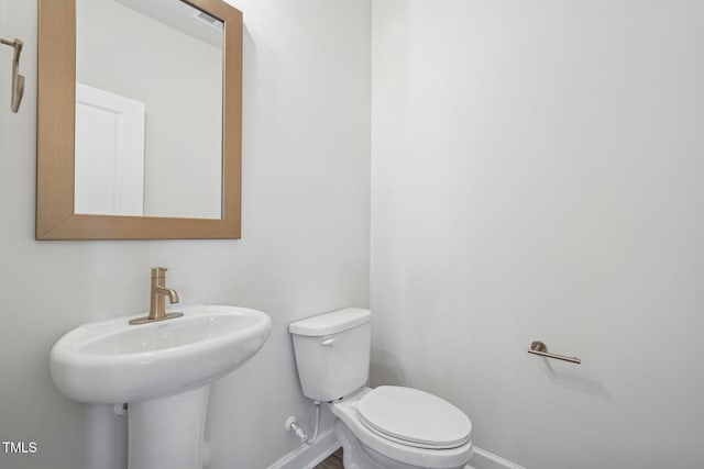 half bath with a sink, toilet, and baseboards