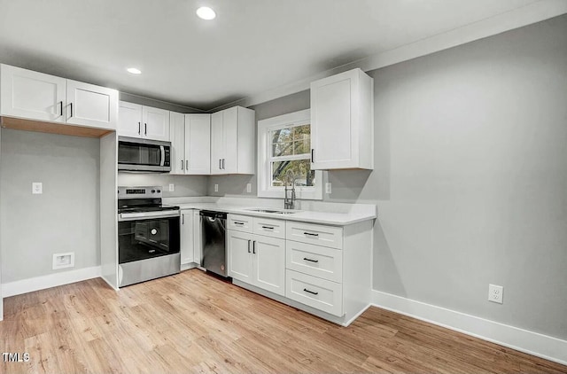 kitchen with appliances with stainless steel finishes, light countertops, white cabinetry, and light wood-style flooring