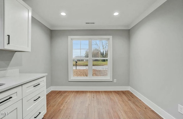 unfurnished dining area with recessed lighting, visible vents, baseboards, ornamental molding, and light wood-type flooring