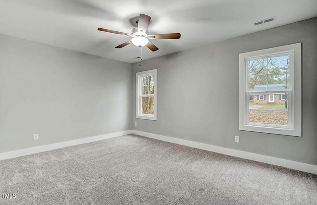 carpeted empty room featuring visible vents, ceiling fan, and baseboards