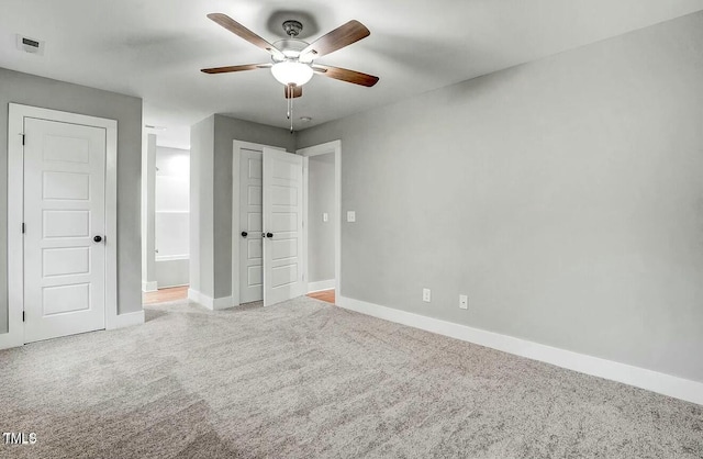 unfurnished bedroom featuring ensuite bathroom, carpet floors, a ceiling fan, visible vents, and baseboards