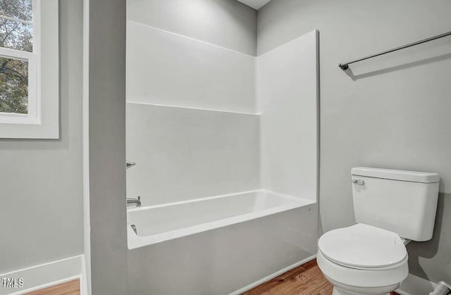 full bathroom with bathtub / shower combination, wood finished floors, and toilet