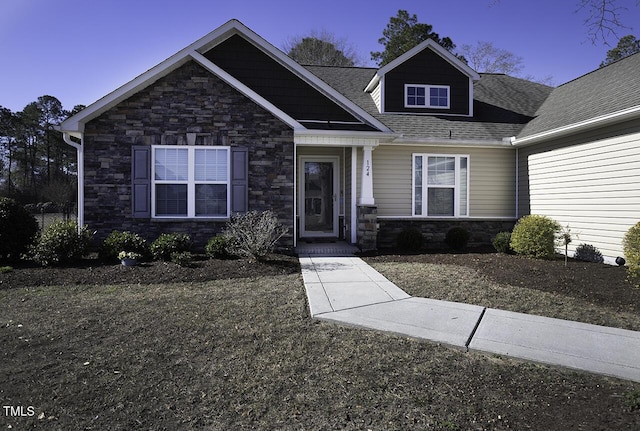 craftsman-style home featuring a shingled roof and stone siding