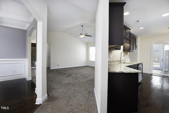 kitchen featuring light stone counters, tasteful backsplash, lofted ceiling, a ceiling fan, and a sink