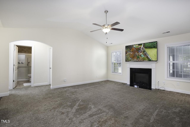 unfurnished living room with arched walkways, lofted ceiling, carpet flooring, a fireplace with flush hearth, and visible vents