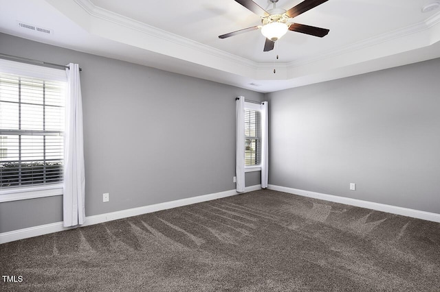 empty room with carpet floors, ornamental molding, a raised ceiling, and baseboards