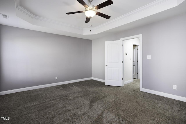 interior space with dark colored carpet, ornamental molding, a raised ceiling, and baseboards