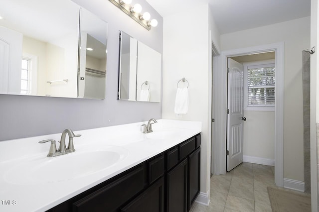 full bath featuring double vanity, tile patterned flooring, a sink, and baseboards