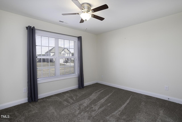 empty room with dark colored carpet, visible vents, and baseboards