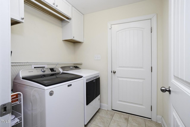 clothes washing area with cabinet space, light tile patterned floors, baseboards, and separate washer and dryer