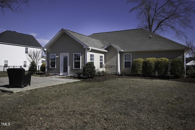 rear view of house with a yard, a patio, a shingled roof, and fence