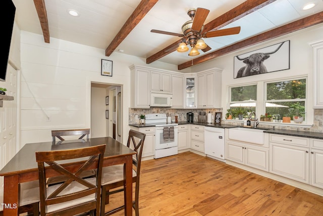 kitchen with a sink, white appliances, backsplash, and light wood-style floors