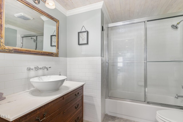 bathroom with toilet, vanity, tile walls, combined bath / shower with glass door, and crown molding