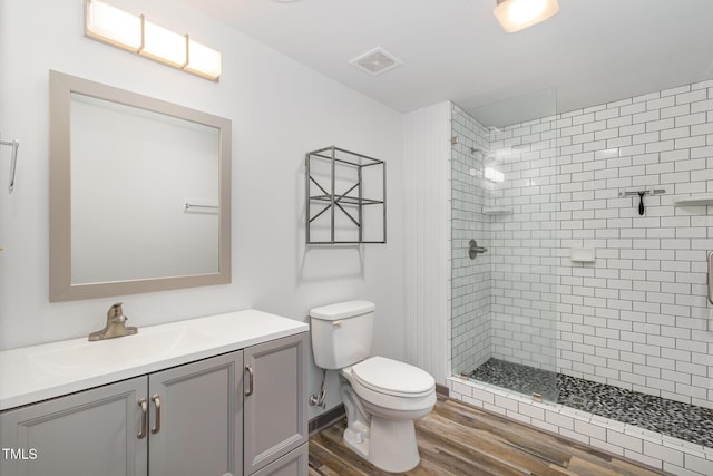 bathroom with visible vents, toilet, a stall shower, vanity, and wood finished floors