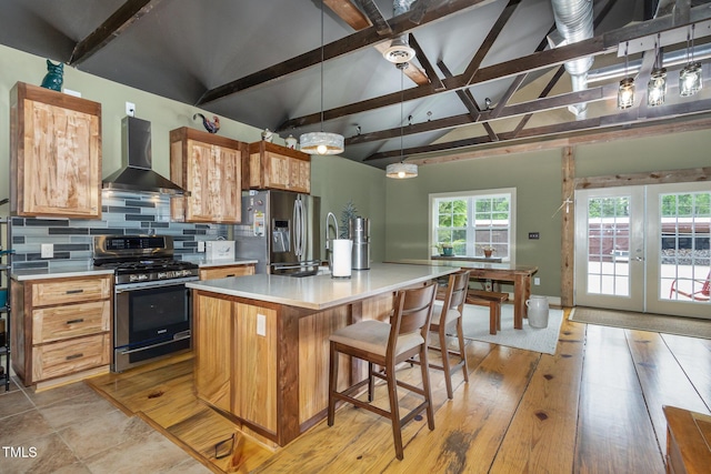 kitchen with lofted ceiling with beams, stainless steel appliances, light countertops, wall chimney range hood, and backsplash