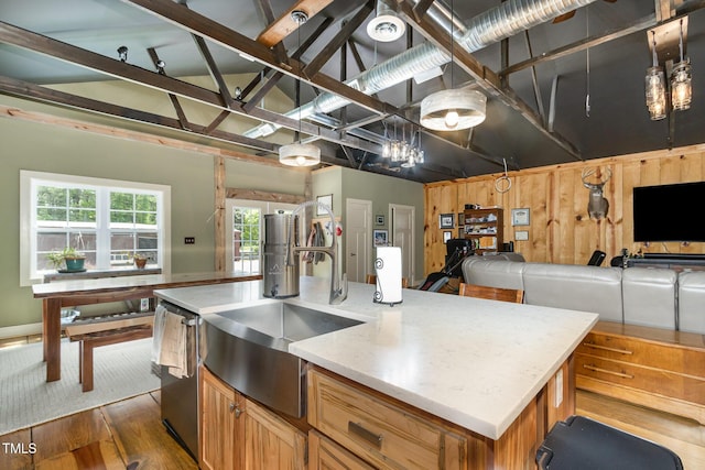 kitchen with dark wood-style flooring, stainless steel dishwasher, open floor plan, a kitchen island with sink, and a sink