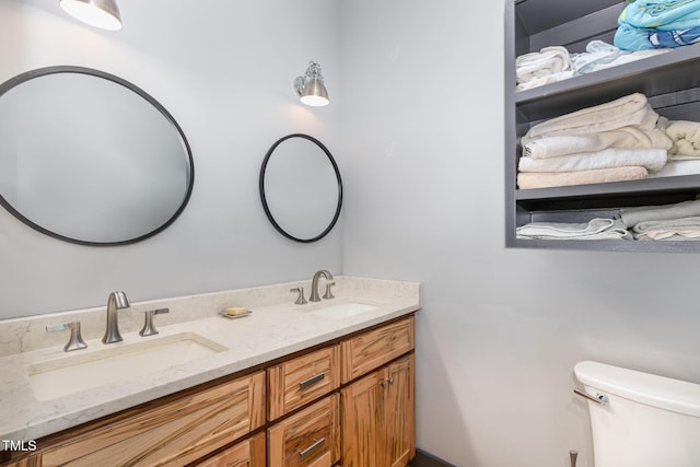 bathroom with double vanity, a sink, and toilet