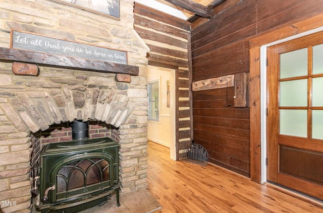 room details featuring a wood stove, wood walls, beam ceiling, and wood finished floors