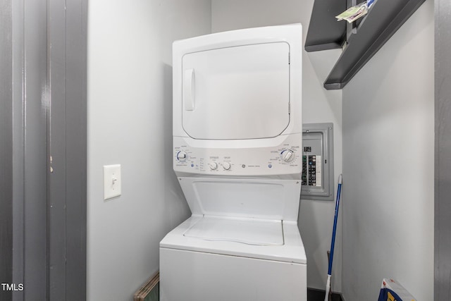 laundry area featuring laundry area, electric panel, and stacked washing maching and dryer