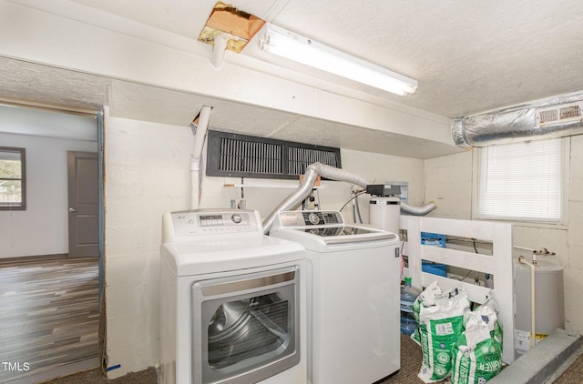 clothes washing area with a textured ceiling, laundry area, separate washer and dryer, and wood finished floors