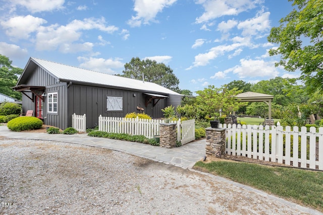 view of front of house with board and batten siding, metal roof, and a fenced front yard