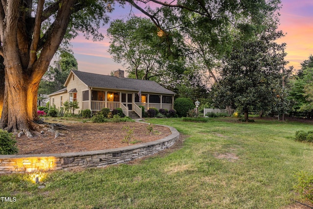 view of front of property featuring a porch, a lawn, and a chimney