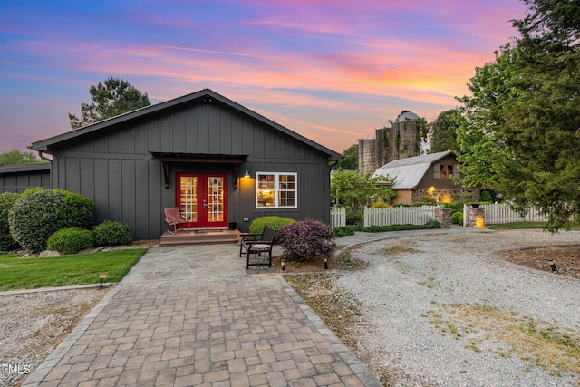 view of front facade with driveway, french doors, board and batten siding, and fence