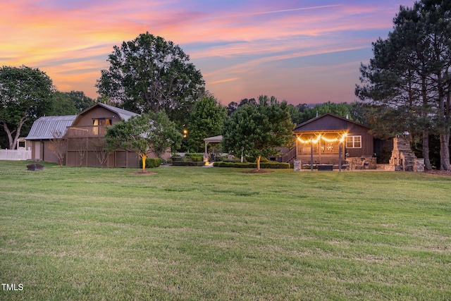 yard at dusk with a barn, a garage, and an outbuilding