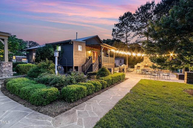 back of property with a patio area, a yard, and stairs