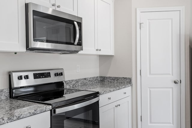 kitchen featuring stainless steel appliances, white cabinetry, and light stone countertops