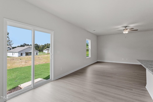 unfurnished living room with a ceiling fan, baseboards, and wood finished floors