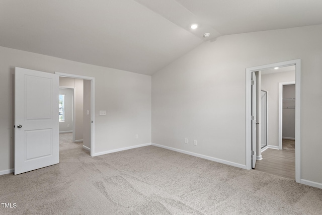 interior space featuring a walk in closet, carpet, baseboards, and vaulted ceiling