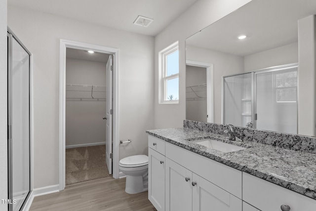 full bath with toilet, vanity, visible vents, a spacious closet, and a shower stall