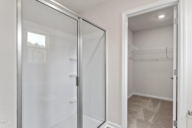 bathroom featuring a stall shower, a spacious closet, and baseboards