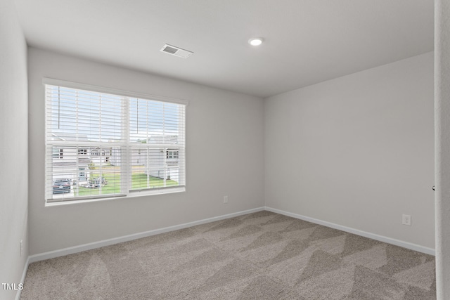 carpeted spare room featuring visible vents and baseboards