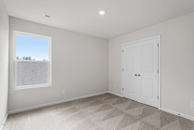 unfurnished bedroom featuring a closet, carpet, visible vents, and baseboards