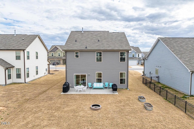 rear view of property featuring a patio area, a lawn, a fire pit, and fence