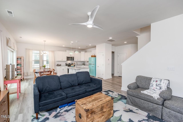 living area featuring light wood finished floors, ceiling fan, and visible vents