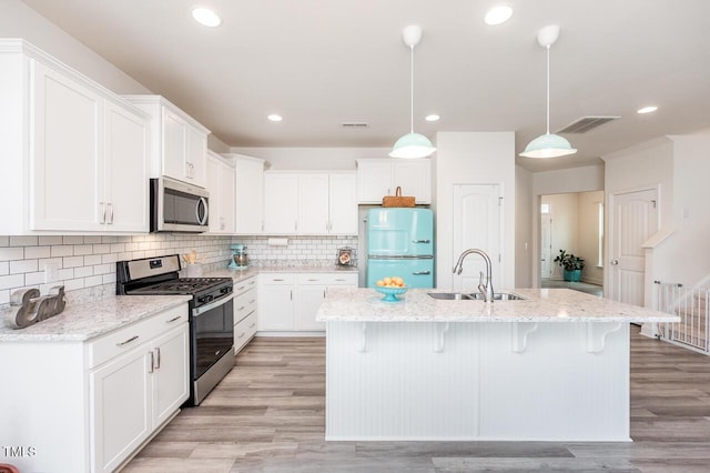 kitchen with white cabinets, a breakfast bar area, stainless steel appliances, and a sink