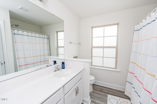 full bath featuring toilet, wood finished floors, vanity, visible vents, and baseboards