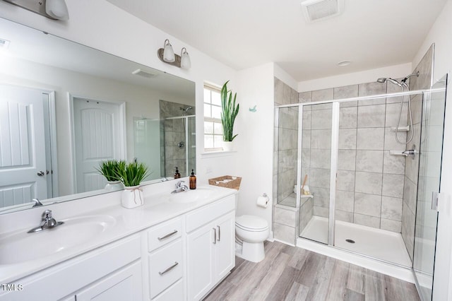 bathroom featuring a stall shower, visible vents, a sink, and wood finished floors